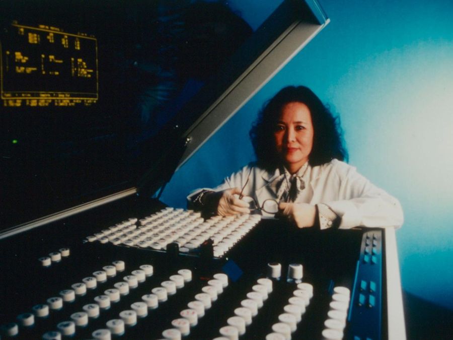 A scientist seated beside rows of sample tubes